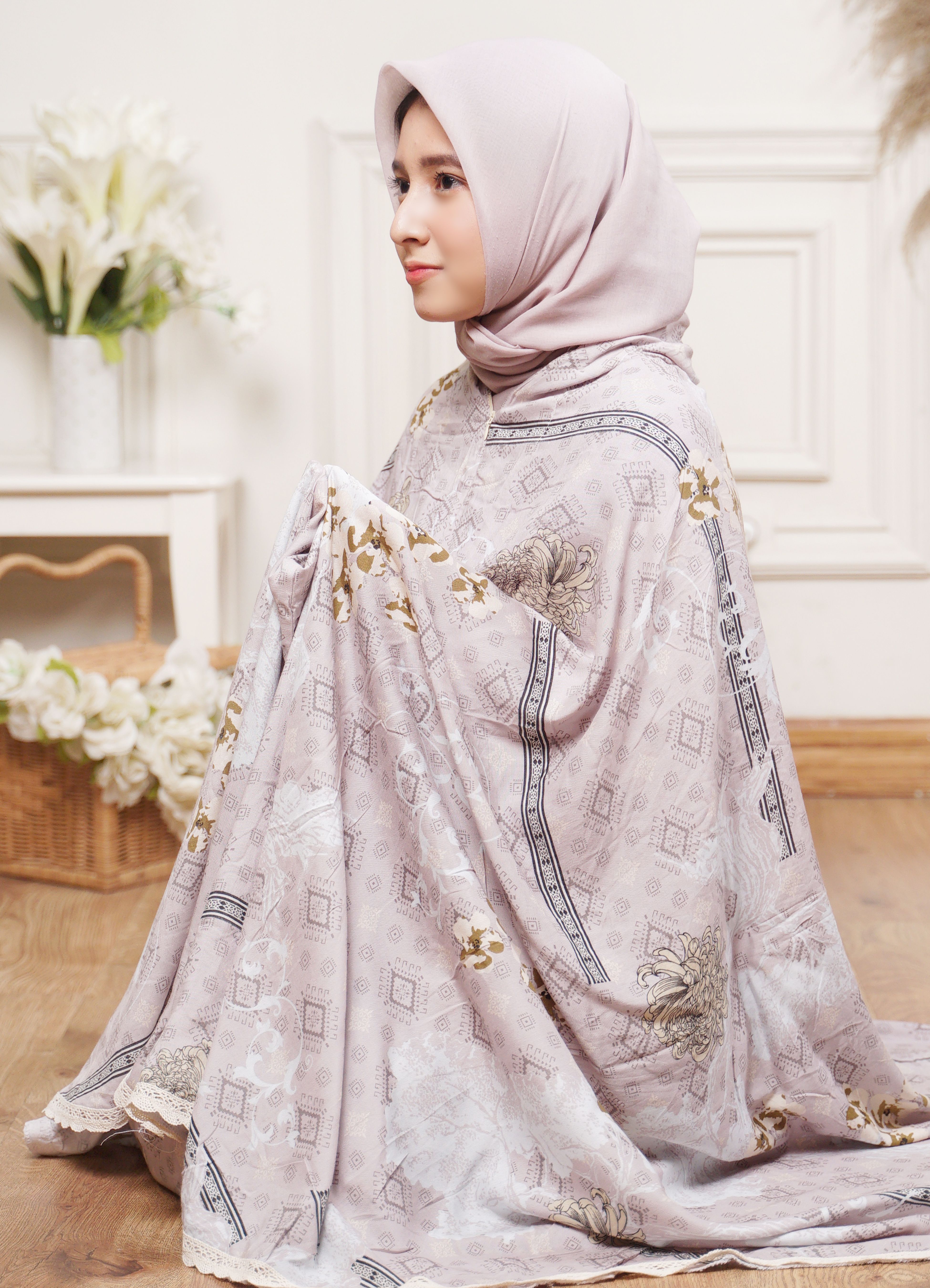 Side profile of a young woman wearing a hijab and floral prayer garment indoors