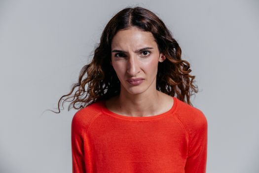 A woman in a red sweater showing a serious and disgusted facial expression.