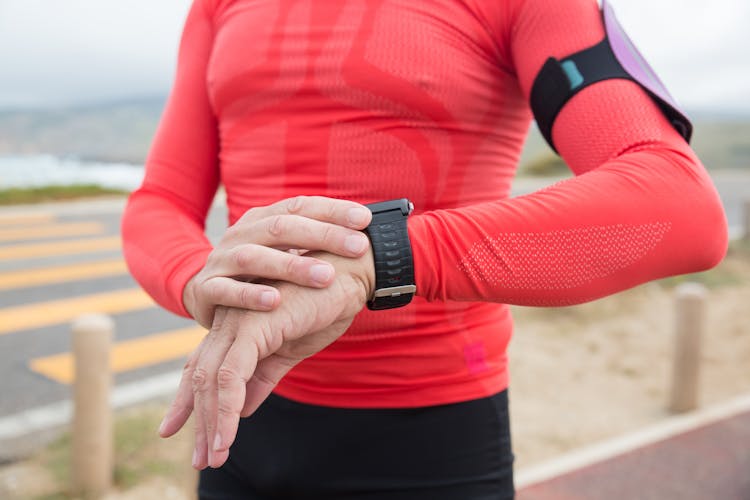 A Person In Red Long Sleeves Activewear Looking At The Wristwatch He Is Wearing