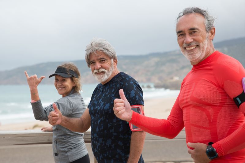 Smiling senior friends exercising together on a beach — social connection and natural movement for longevity