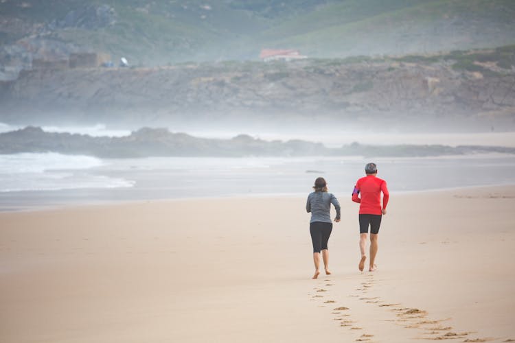 An Elderly Man And A Woman Jogging At TheBeach