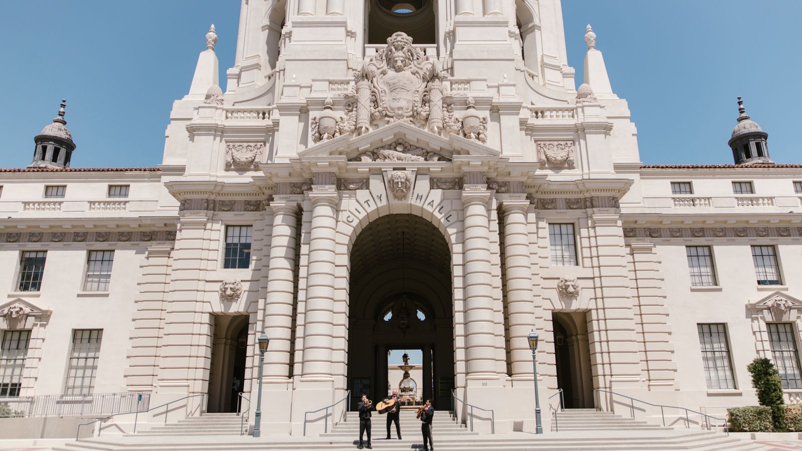 Mariachi band playing in front of the iconic Pasadena City Hall on a sunny day.
