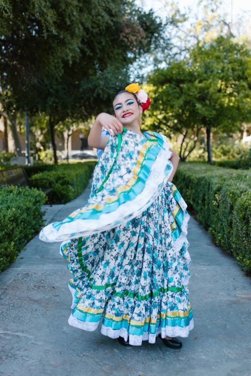 Free Woman in vibrant traditional Mexican dress joyfully dancing in a park. Bright and cultural scene. Stock Photo