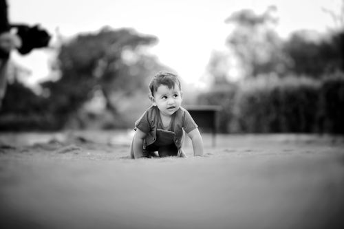 Free Cute baby crawling on grass outdoors in a black and white photo, capturing innocence and curiosity. Stock Photo