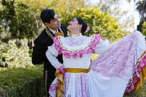 Free A couple dances in colorful traditional Mexican attire in a lush outdoor setting. Stock Photo
