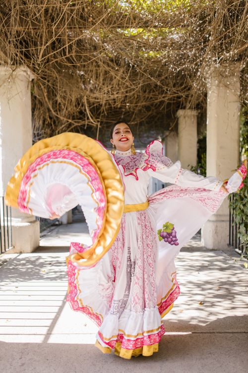 Free Hispanic woman in vibrant traditional dress dancing joyfully outdoors. Stock Photo