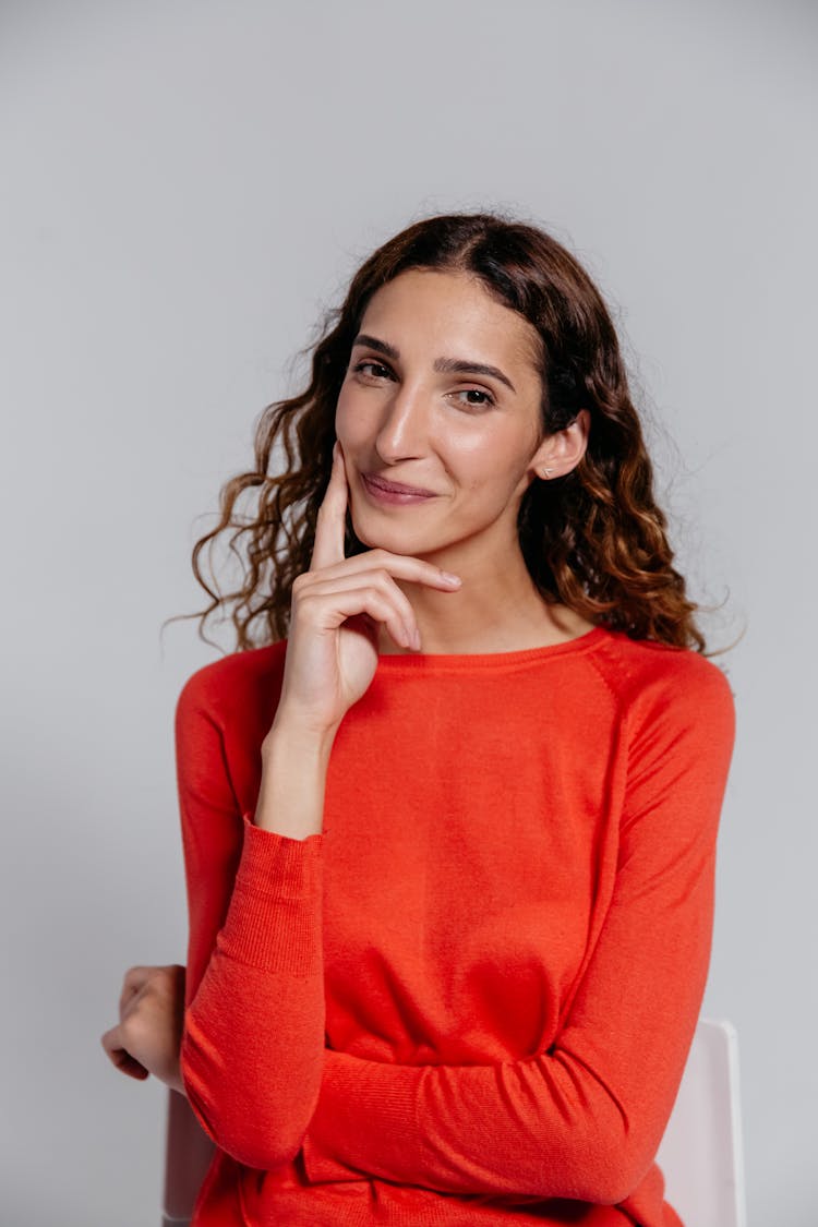 Woman In Red Long Sleeve Shirt With Hand On Cheek