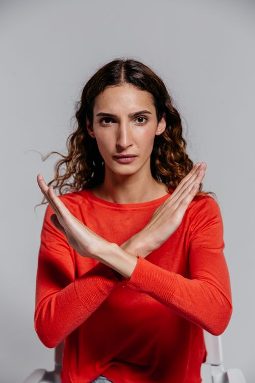 Free Woman in red shirt crossing arms in stop gesture, studio indoor portrait. Stock Photo