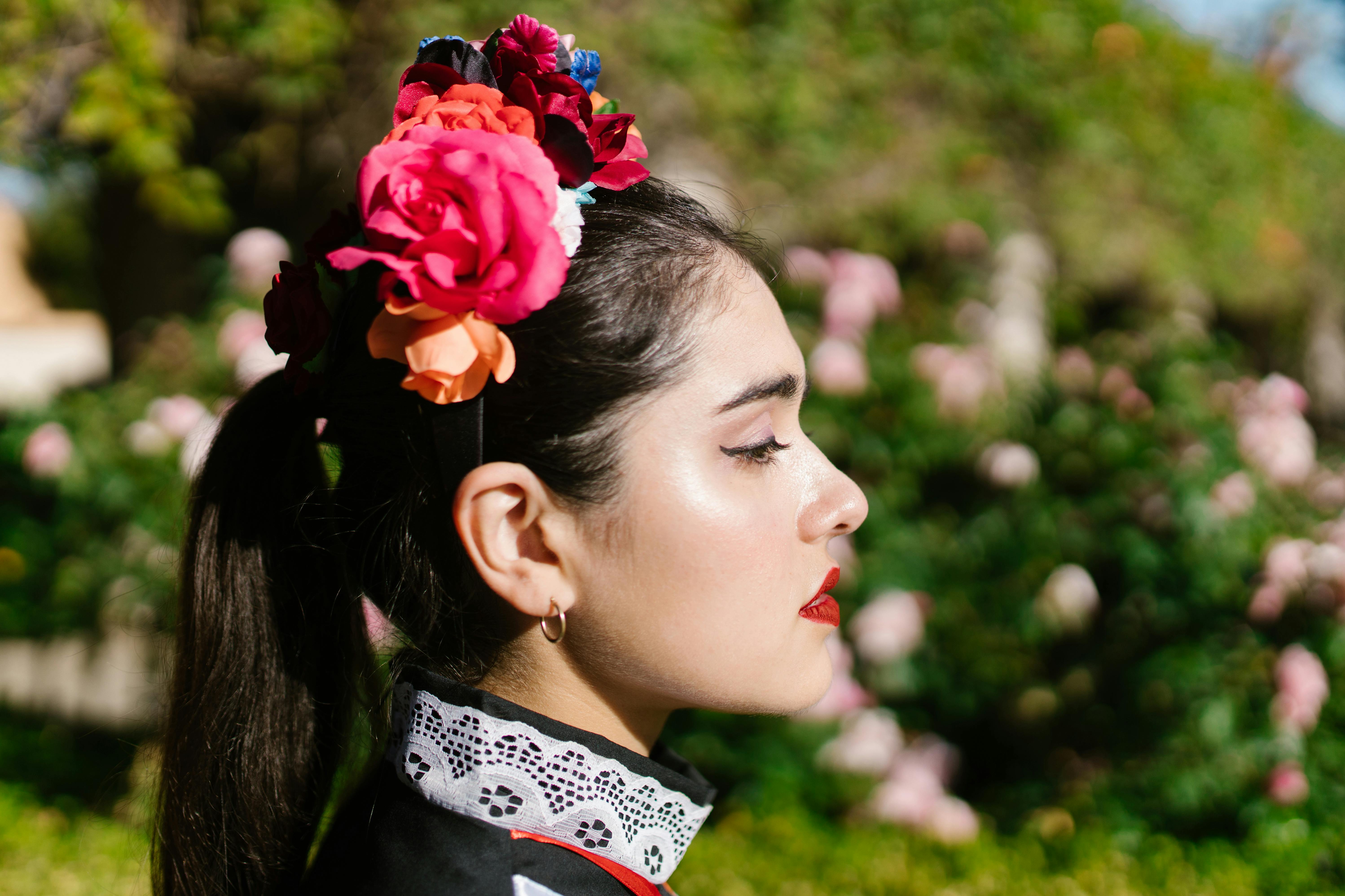Profile of a woman wearing a vibrant flower headband in an outdoor setting.
