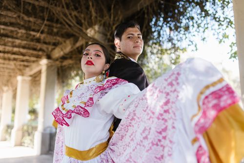 Free Young couple wearing traditional Mexican attire performing a vibrant dance outdoors. Stock Photo