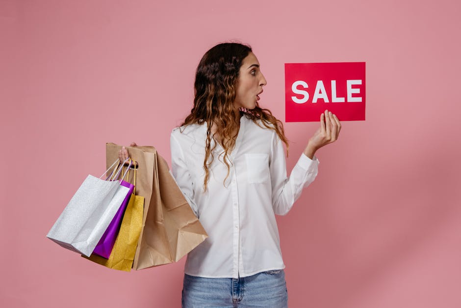 A surprised woman holding shopping bags and a sale sign against a pink background.