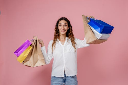 Woman in White Dress Shirt and Blue Denim Jeans Holding Shopping Bags