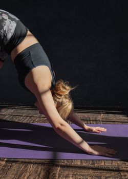 Adult woman doing yoga in downward dog pose, promoting healthy lifestyle and fitness.