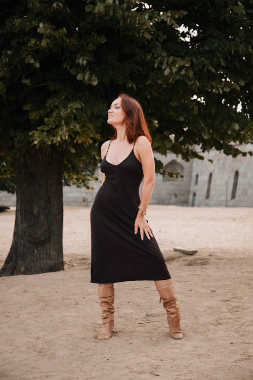 Woman in a Black Spaghetti Strap Dress Standing on the Sand