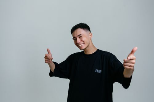 Free A cheerful young man giving a thumbs-up gesture in a studio setting. Stock Photo