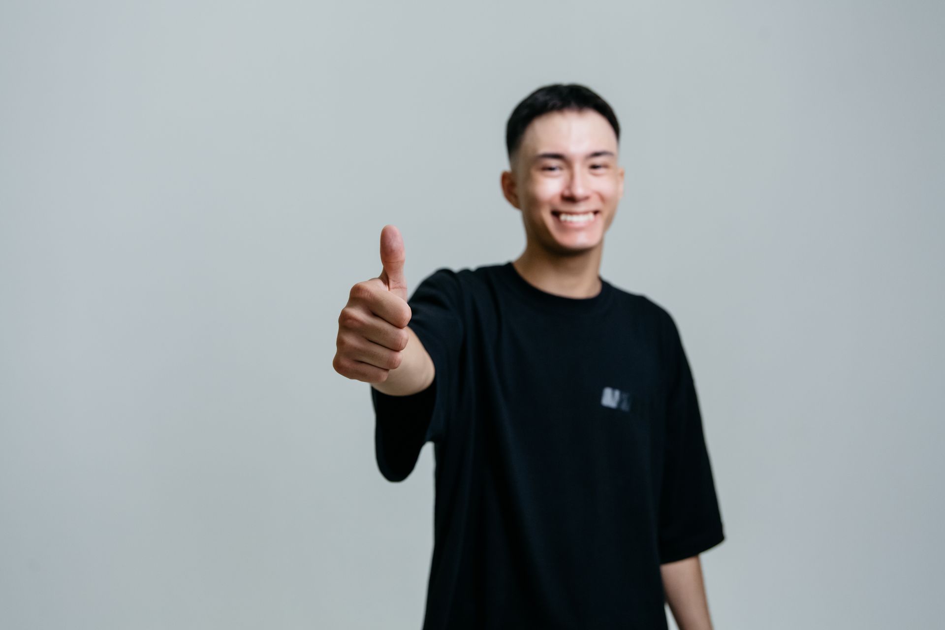Selective Focus Photo of a Man in a Black Shirt Doing the Thumbs Up