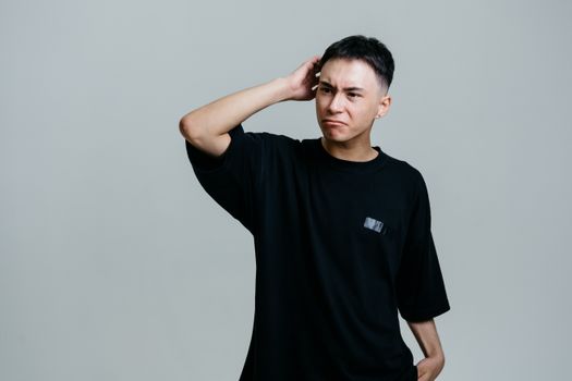 Studio portrait of a young man looking puzzled against a gray background.