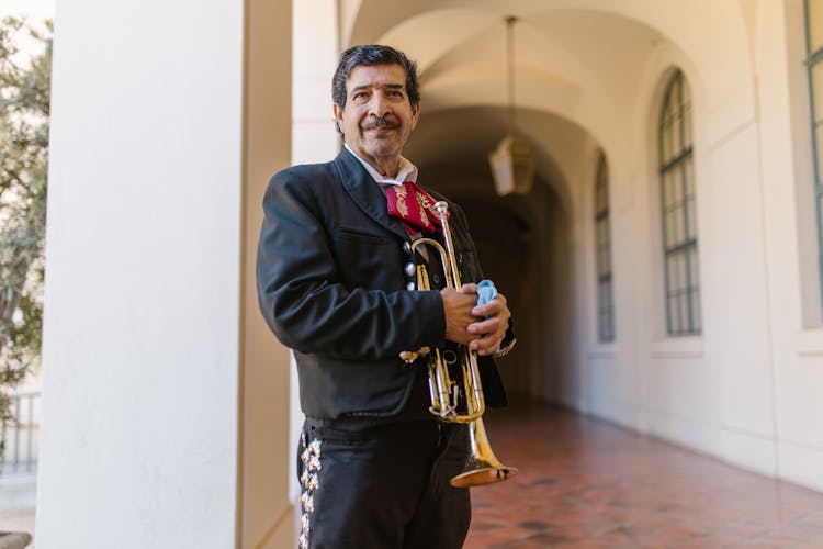 Man In Black Traditional Outfit Holding A Trumpet