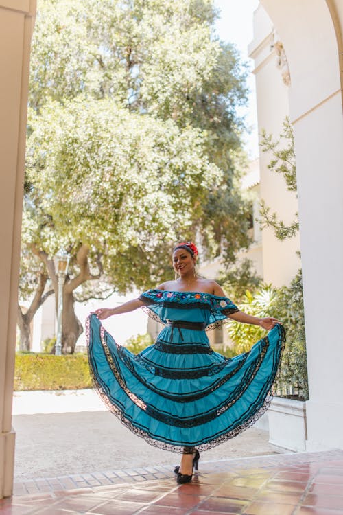 Woman in Blue and Black Dress Holding Her Dress 