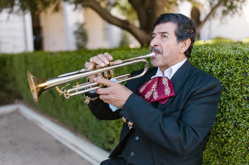 A Man in Black and Red Suit Playing Trumpet