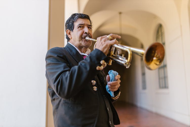 A Man In Black Suit Playing A Trumpet