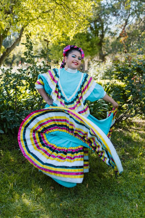 Free Woman in vibrant Mexican folk dress dances outdoors, exuding cultural elegance and joy. Stock Photo