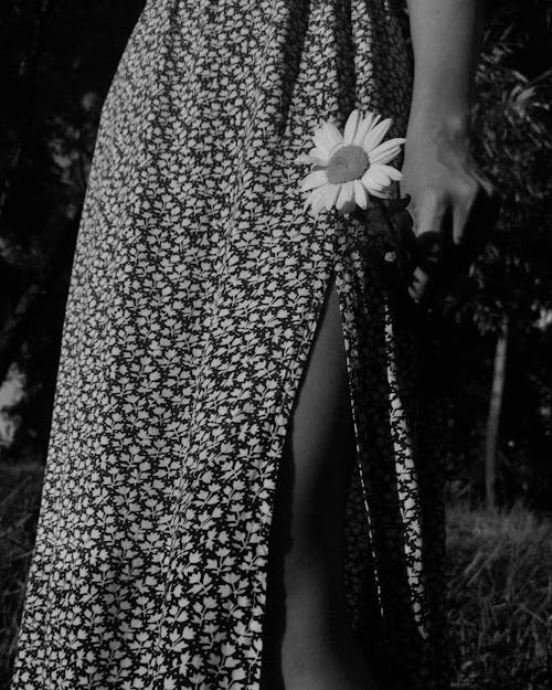 A Grayscale Photo of a Person Wearing Floral Skirt Holding a Flower