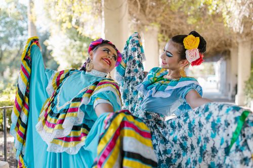 Free Two women in traditional Mexican dresses joyfully dancing outdoors. Stock Photo