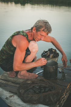Man sorting shellfish on a tranquil lake in Kletskaya, Russia. Outdoor fishing scene.