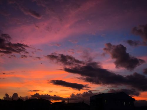 Free Breathtaking sunset featuring vibrant orange and purple cloudscape over silhouettes. Stock Photo