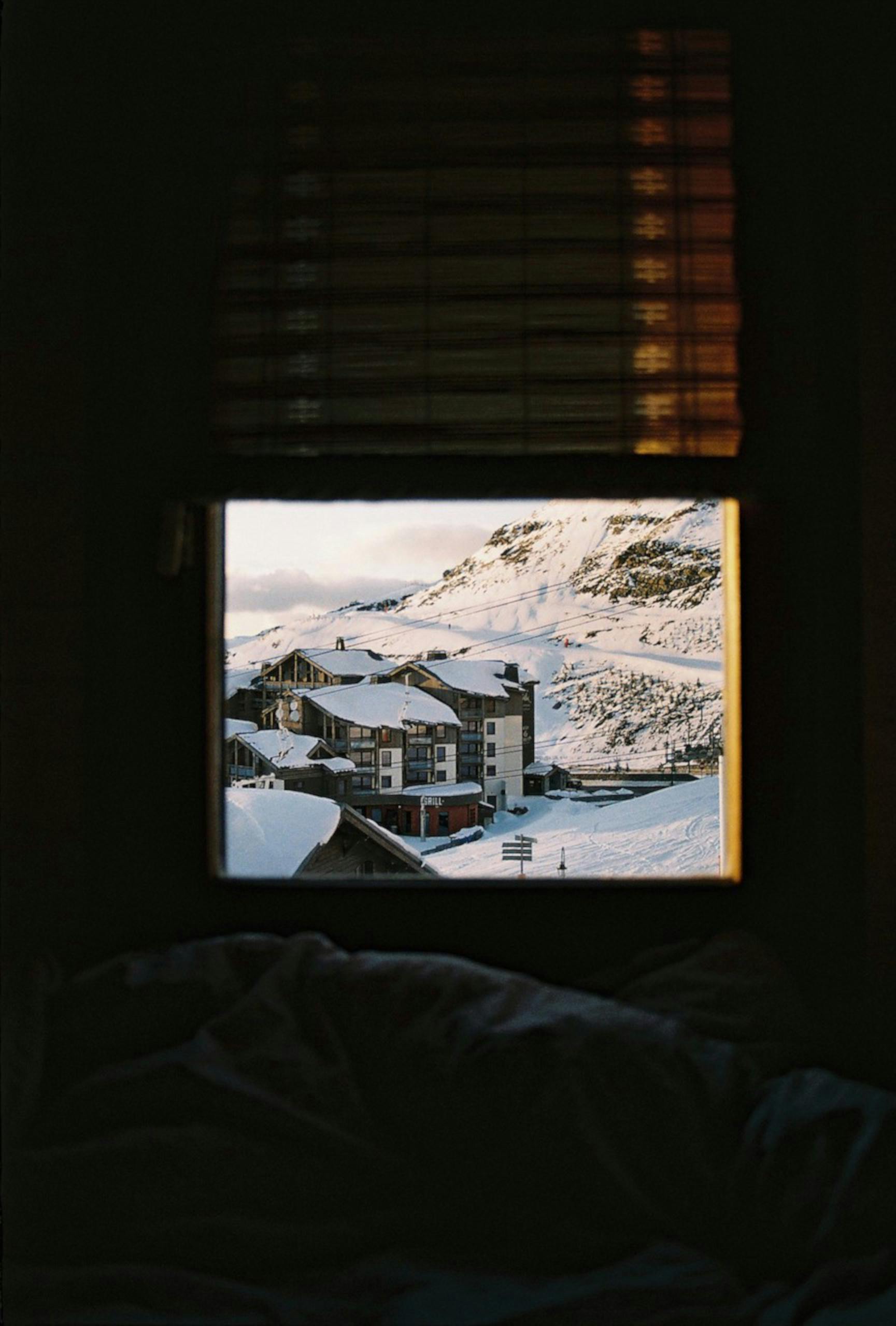 A warm indoor view of snow-covered Val Thorens from a window.