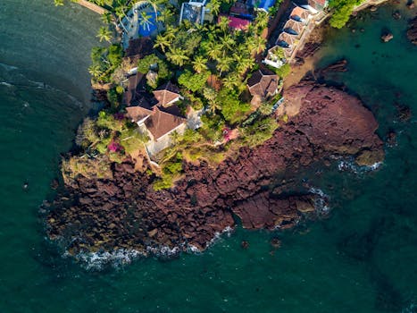 A stunning aerial view of seaside villas surrounded by tropical trees and rocky shores.