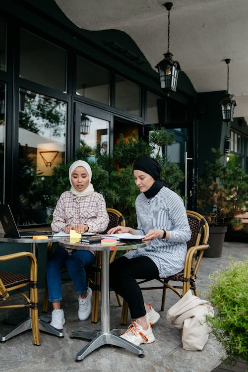 Free Two Women Working on a Table Outside a Coffee Shop Stock Photo