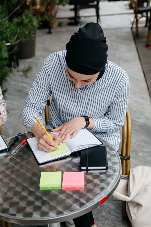 Woman in Striped Long Sleeve Shirt Writing on Notebook · Free Stock Photo