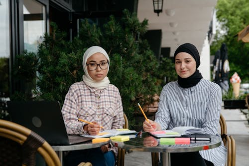 Free Two Women in White and Black Hijabs Studying and Writing on Notebooks  Stock Photo