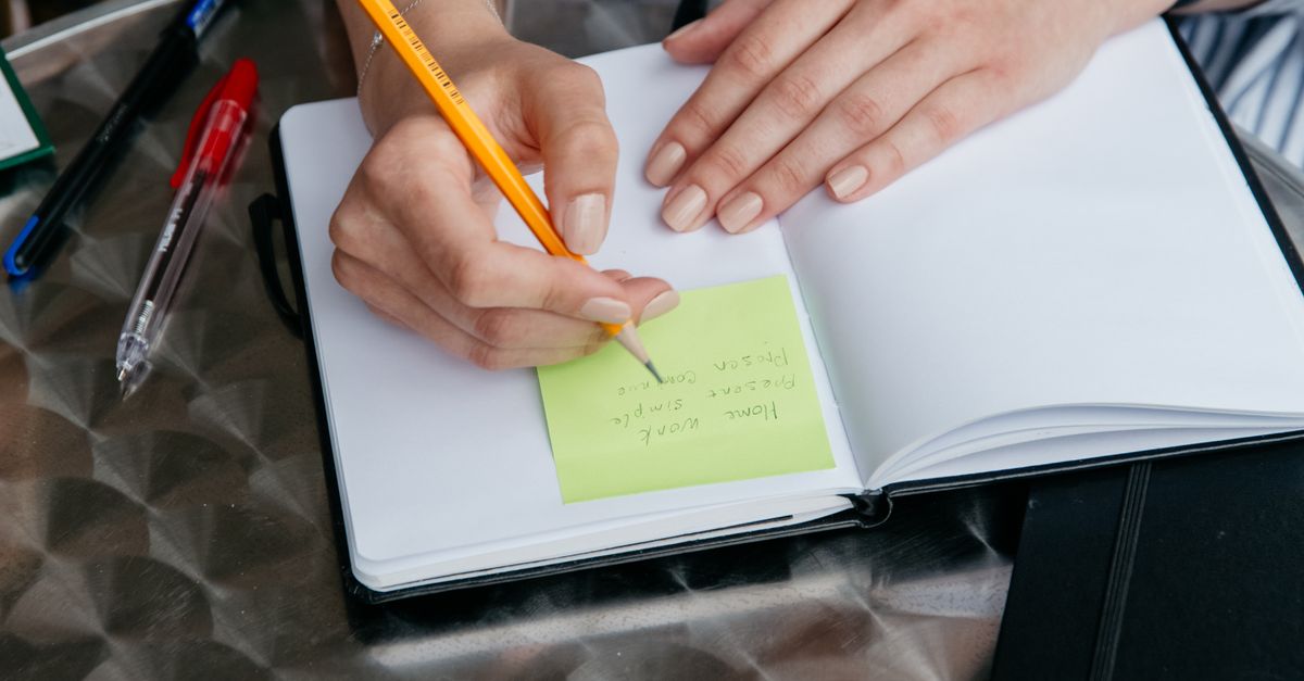 Pen Making Notes Making a Note in Pencil on a Sticky Note in the Planner · Free Stock Photo
