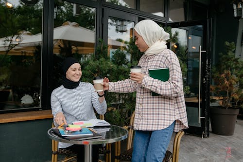 Free Woman Handing a Woman a Cup of Drink Stock Photo