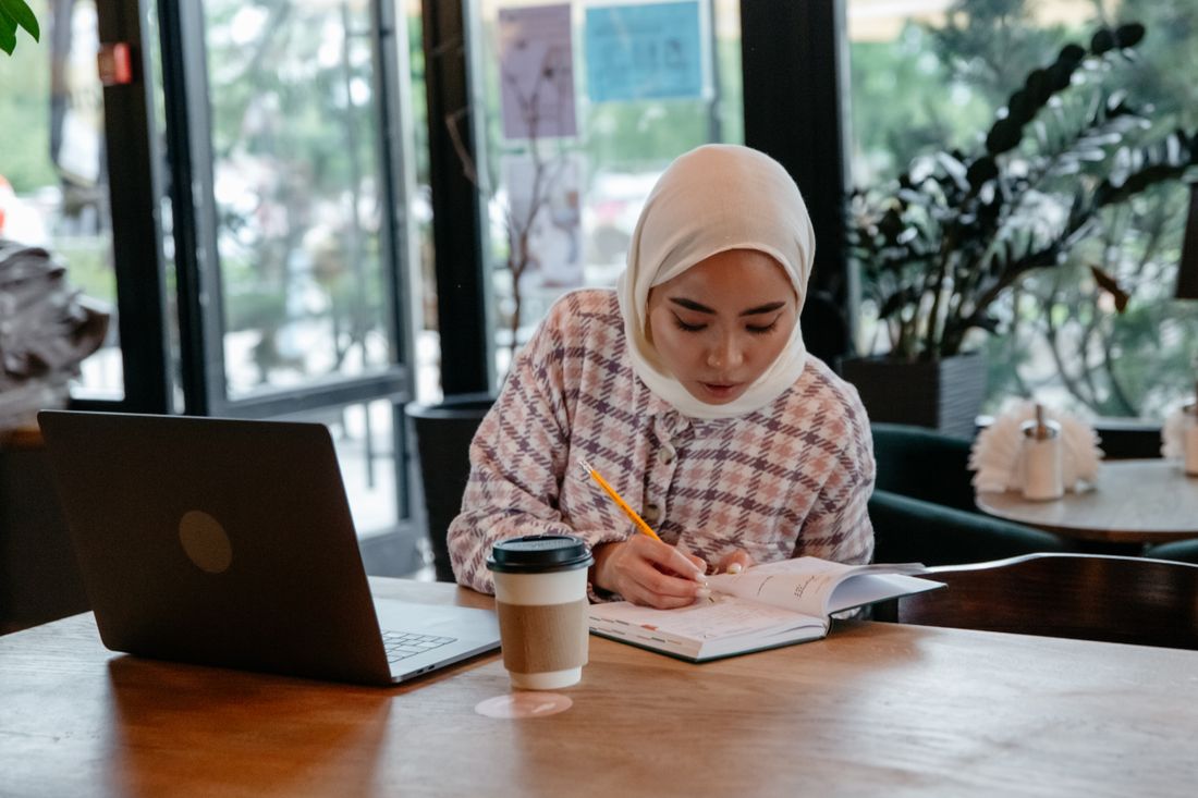 Peserta berhijab belajar TOEFL dengan laptop dan buku catatan