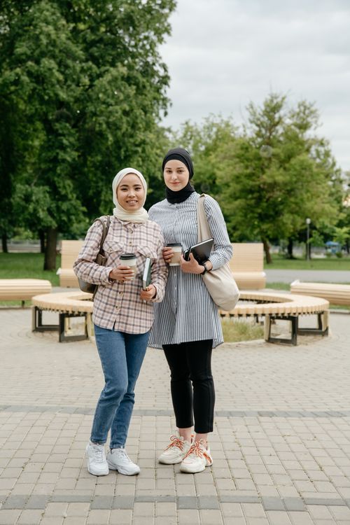 Free Two women in hijabs smiling in an urban park, showcasing fashion and friendship. Stock Photo