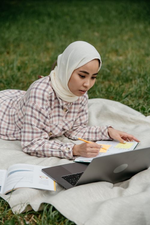 A Woman in White Hijab Writing on a Notebook · Free Stock Photo