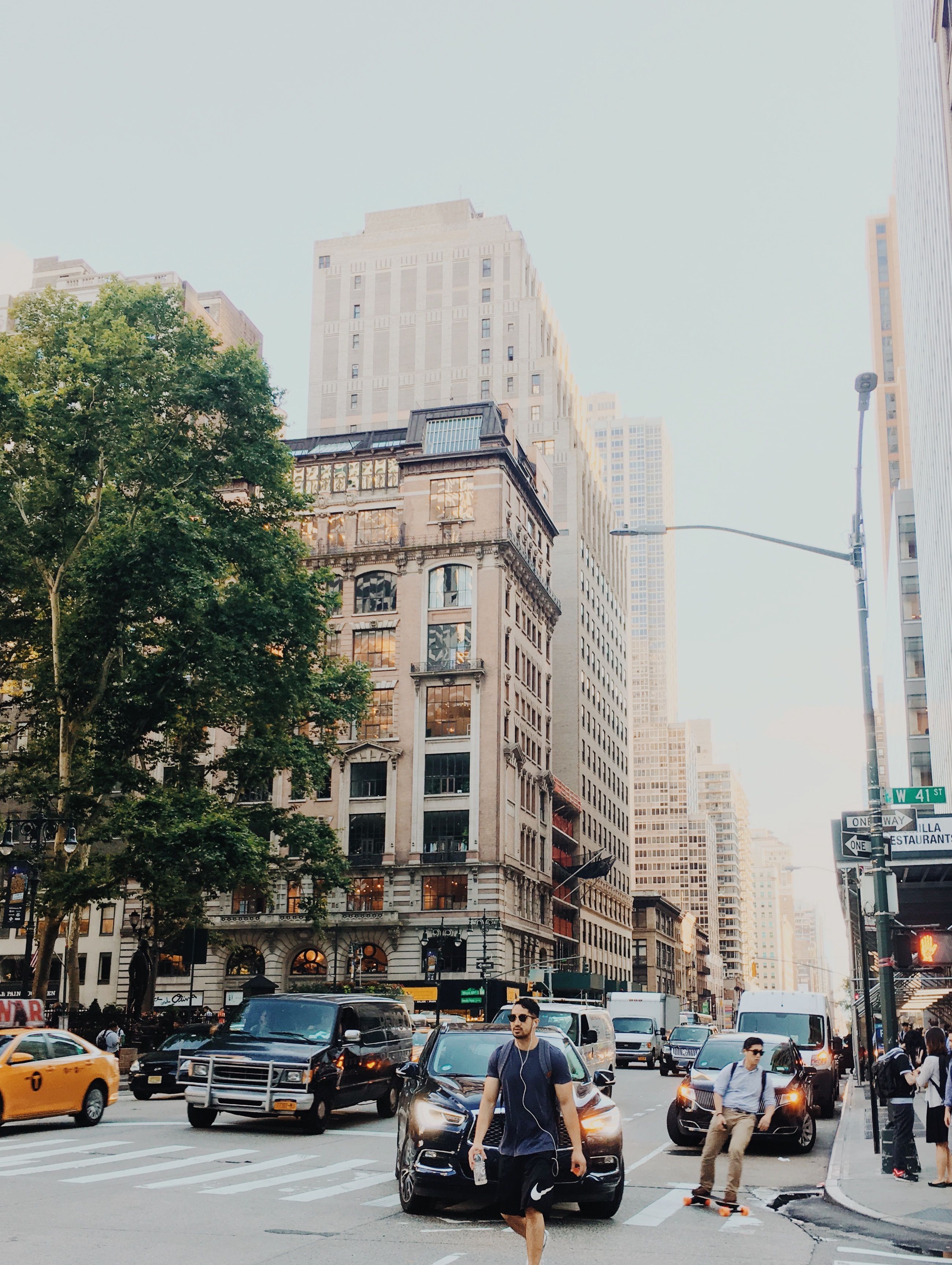 Dynamic city street scene with traffic and pedestrians amidst towering skyscrapers.