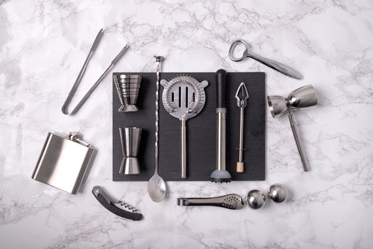 A flat lay of professional bartending tools arranged on a marble surface, ideal for mixology enthusiasts.