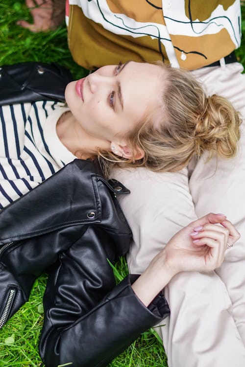 Photo of a Woman in a Black Leather Jacket Lying on a Person's Lap