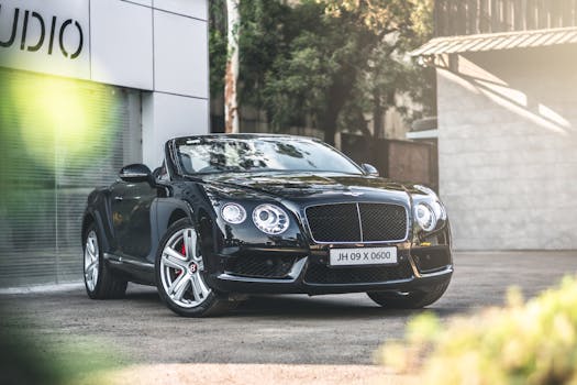 Elegant black Bentley convertible parked by a modern building on a sunlit street.
