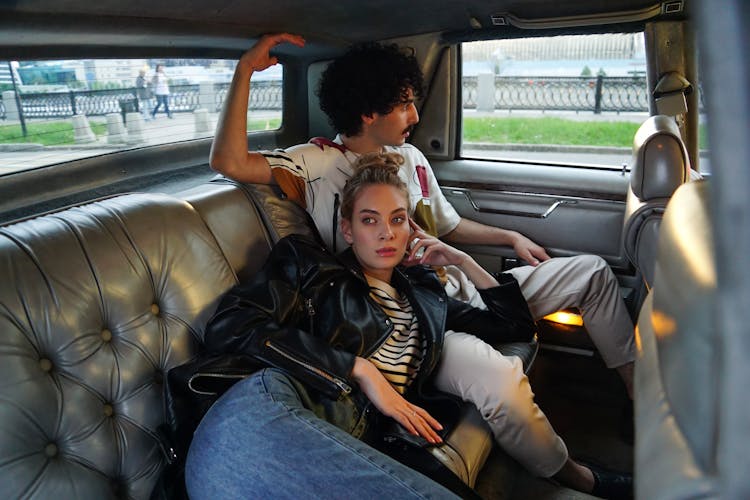 A Man And Woman Sitting On A Leather Car Seat