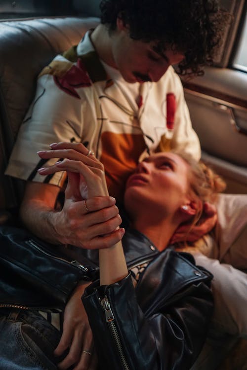 Woman in Leather Jacket Lying on the Lap of a Man