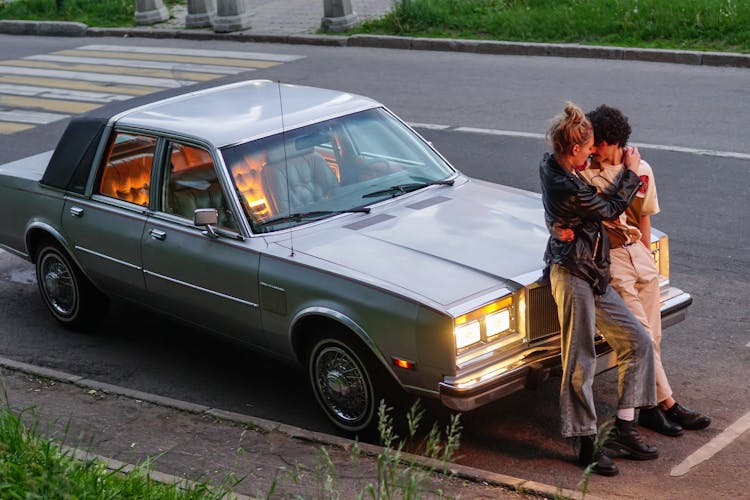 Couple Leaning On Car Parked On Roadside