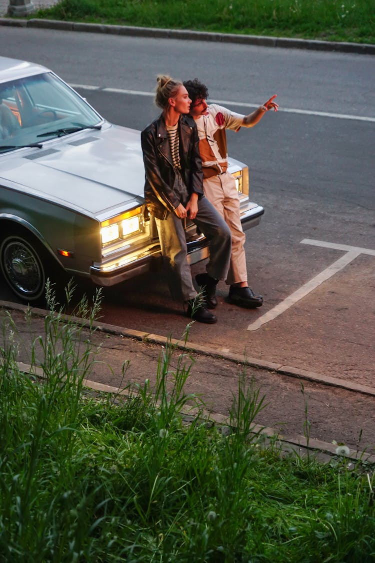 Man And Woman Sitting On Car Hood 