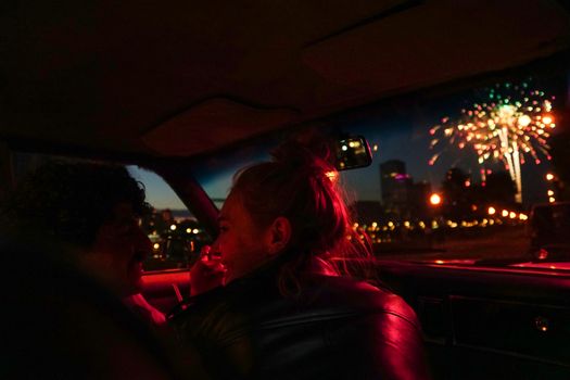 Couple enjoying fireworks from car interior at night, capturing a romantic moment.