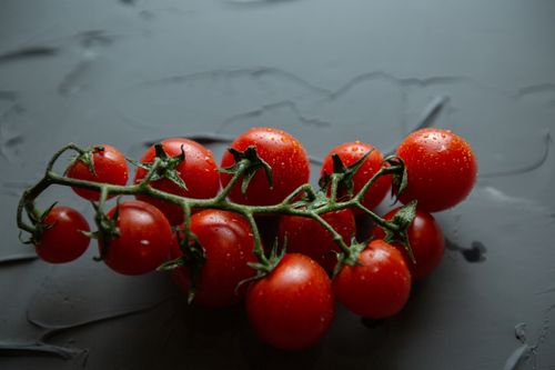 Free Close-up of ripe cherry tomatoes with water droplets on a dark surface, highlighting freshness and texture. Stock Photo